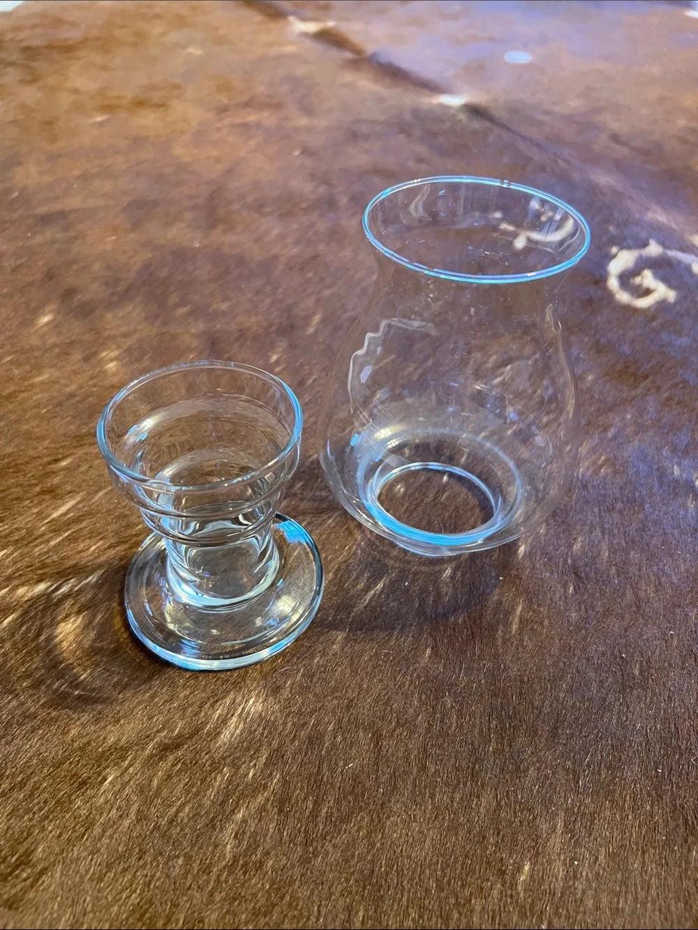 Clear glass hurricane candle holder features a pedestal base and a flared top